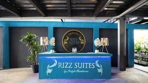A reception desk with a sign for Rizz Suites by InStyle Residences. There are two potted plants and two lamps on the desk. - Penthouse • 2BR 2.5BA • Prime Sosúa Location • 24/7 GYM • Privat Pool • Security (Sosúa)