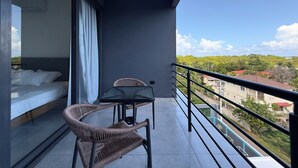 A balcony with a bed, two wicker chairs, and a table. - Penthouse • 2BR 2.5BA • Prime Sosúa Location • 24/7 GYM • Privat Pool • Security (Sosúa)