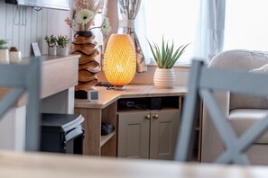 Een moderne woonkamer met een houten bureau, een staande lamp en een plant in pot.