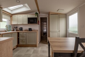 A compact kitchen with a skylight, wooden cabinets, and a microwave.