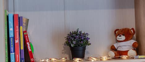 En træhylde med bøger, en potteplante og en bamse.