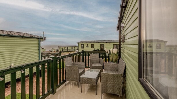 A balcony with wicker furniture and a view of other similar buildings.