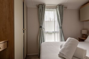 Een hotelkamer met een bed, een houten kledingkast en een raam met gordijnen.