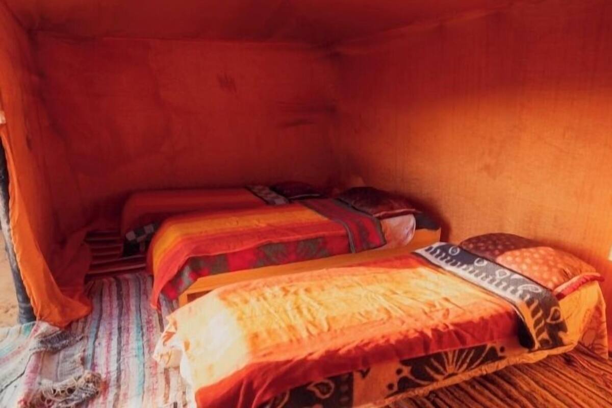 A tent-style room with two beds, each with patterned bedding and pillows.