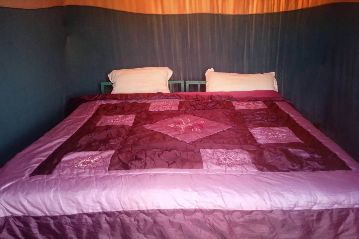 A bed with a patterned quilt, two pillows, and a green headboard.