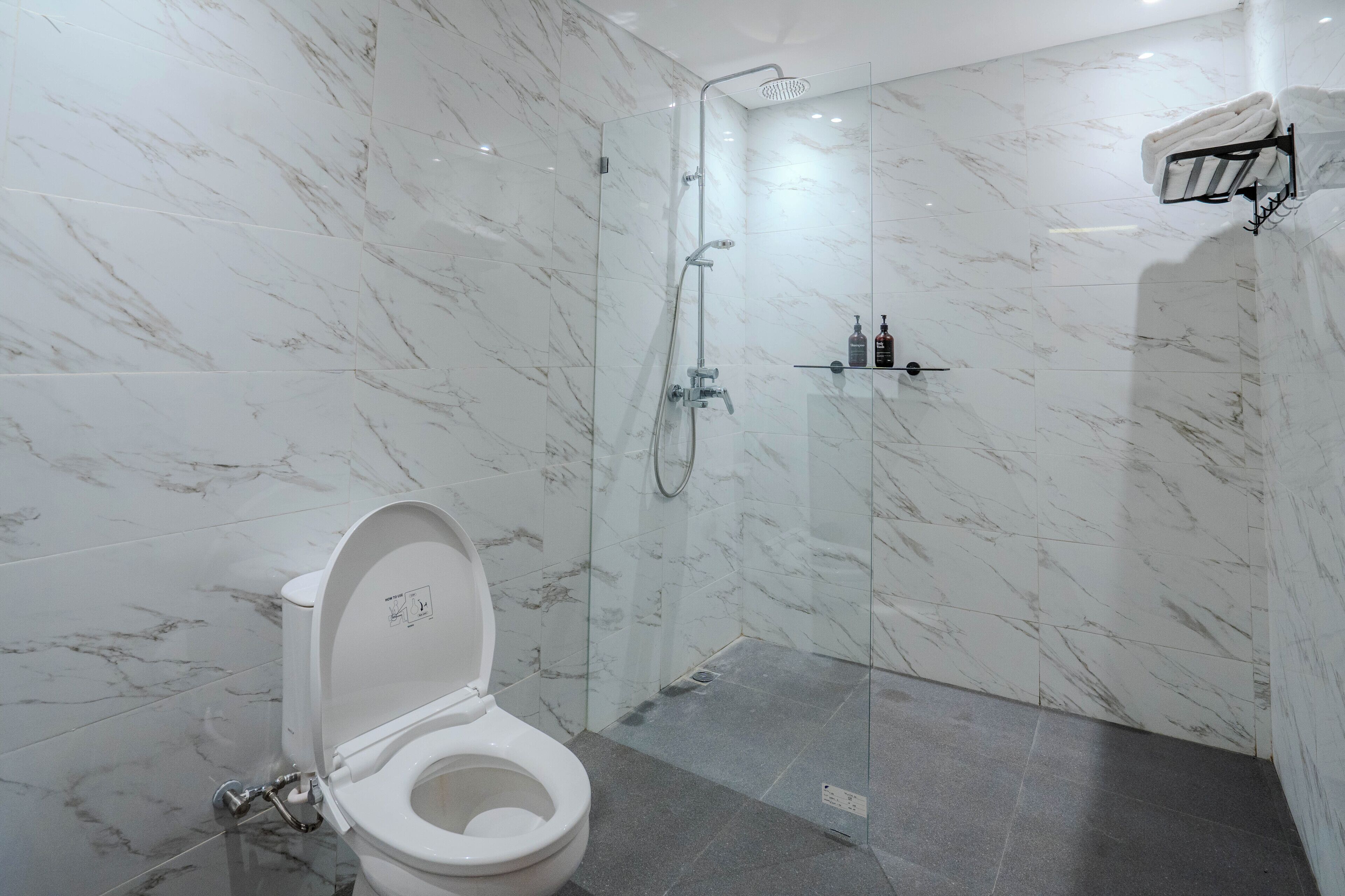 Un bagno moderno con doccia a vetro, un water bianco e pareti in marmo.