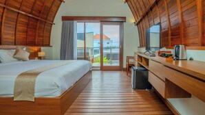 A bedroom with a bed, a desk, a chair, and a view of the outside. - Villa Radha Pererenan (Pererenan)