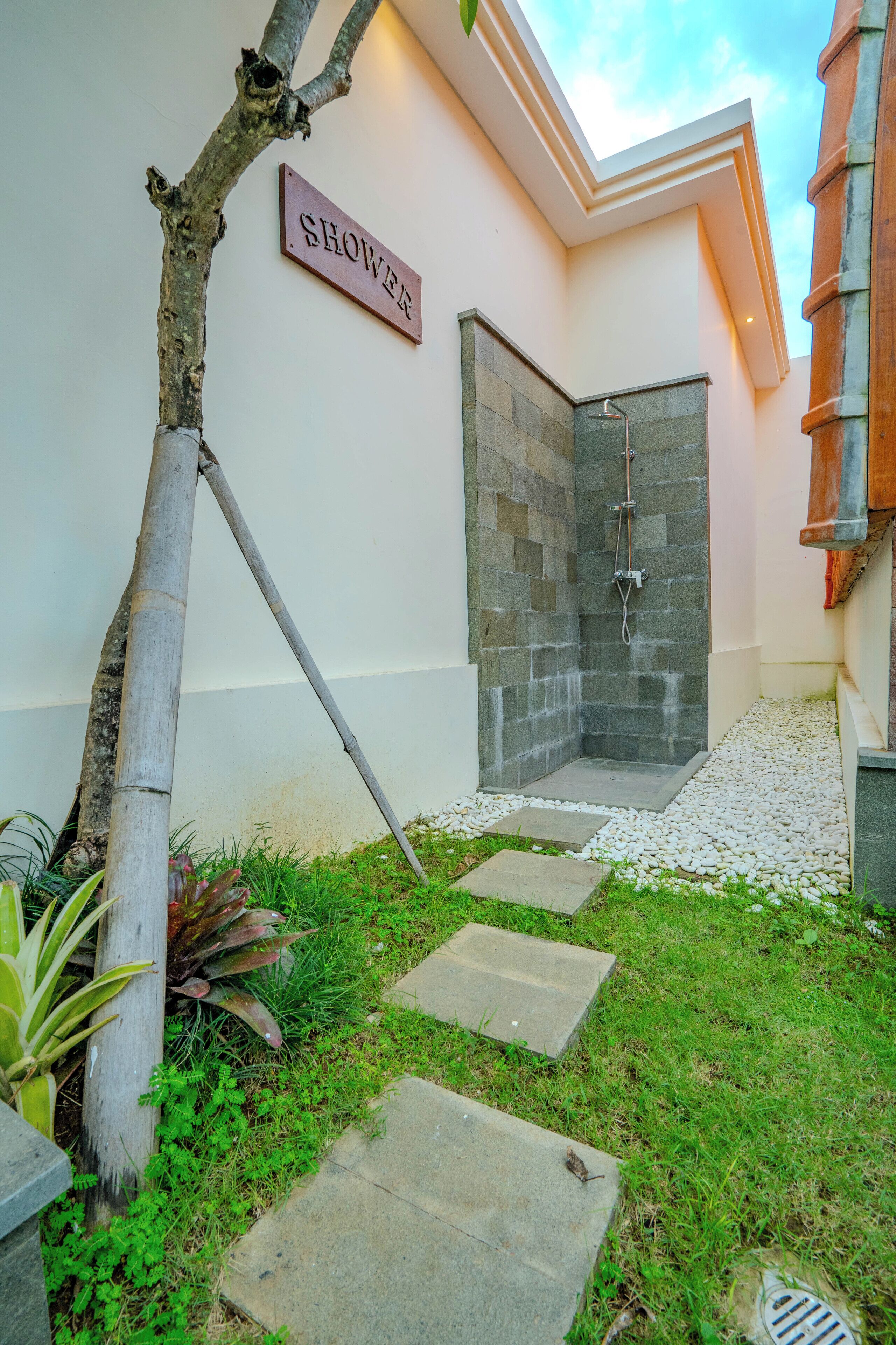 A modern shower area with a stone wall and a sign labeled "SHOWER".