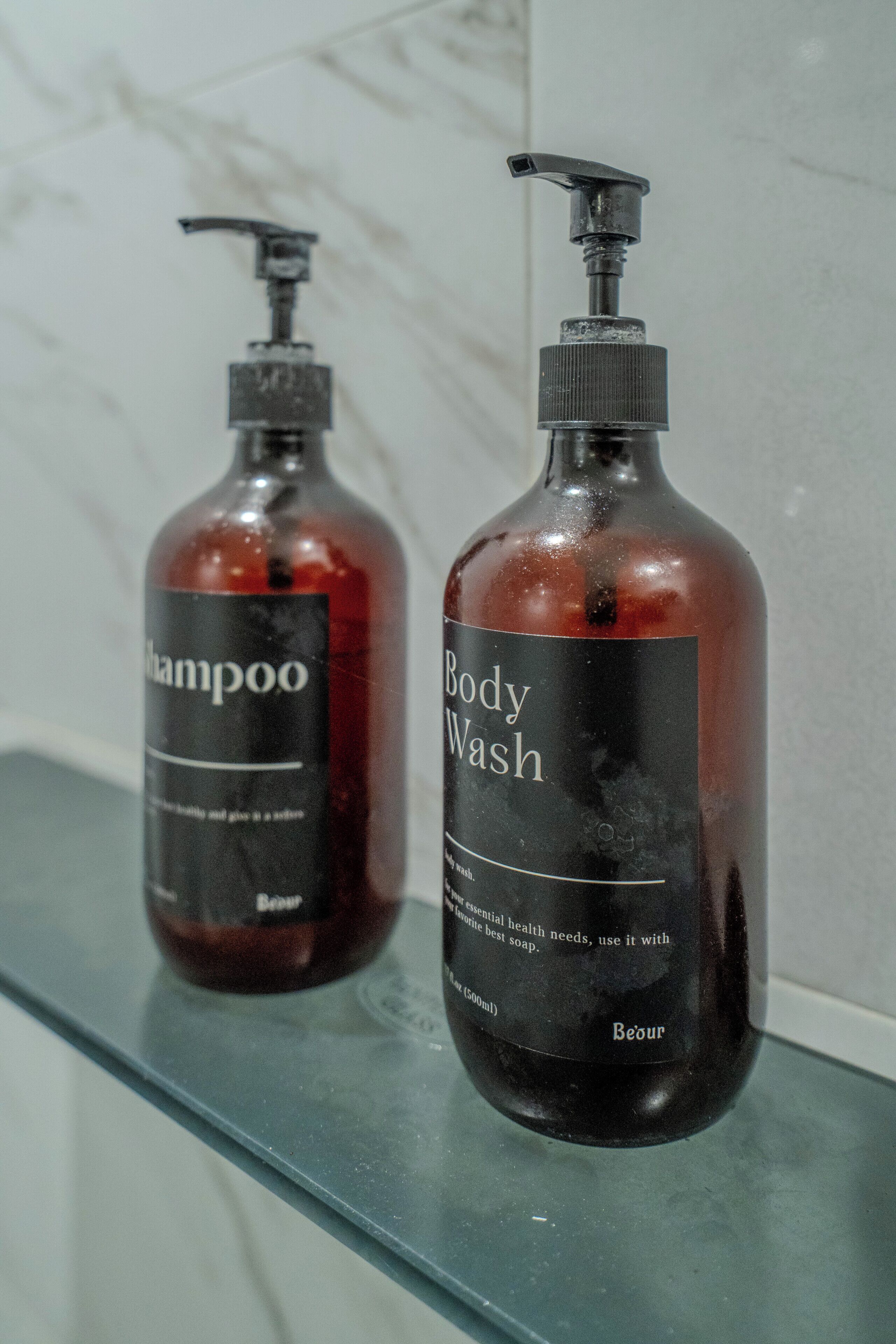 Two bottles of shampoo and body wash on a bathroom counter.