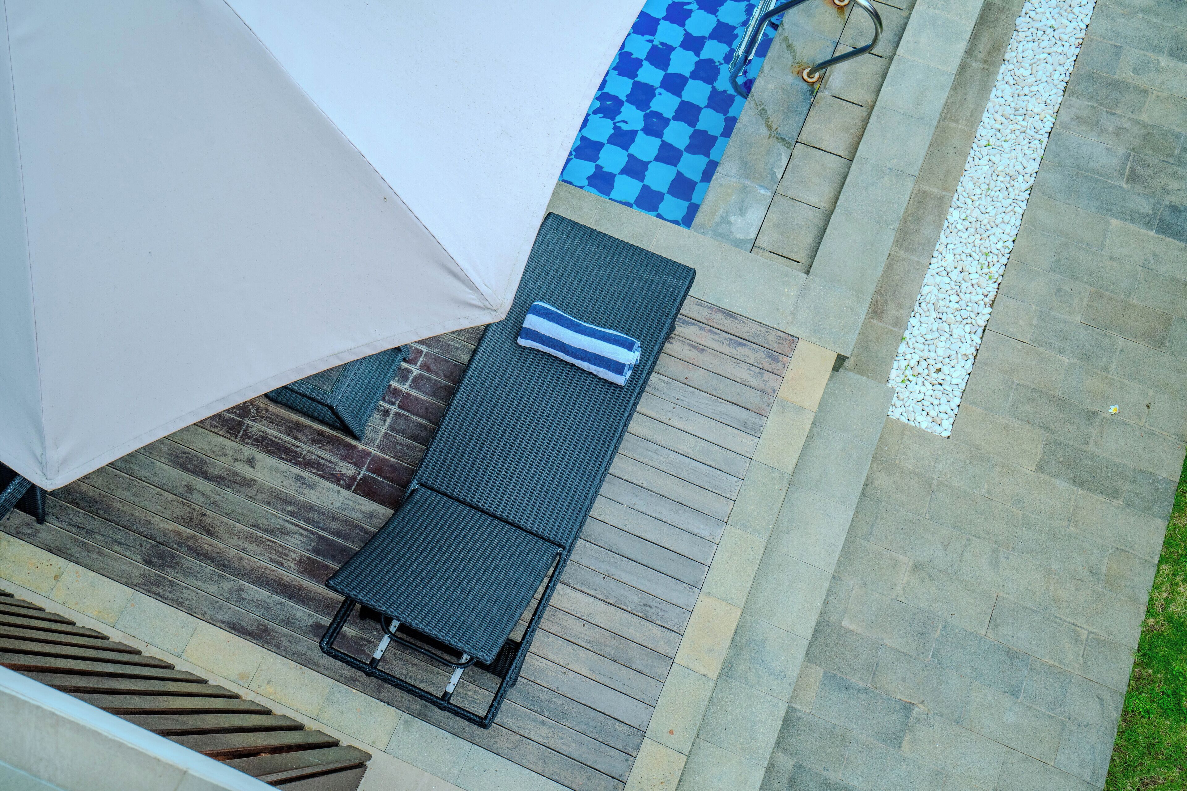 A rooftop terrace with a checkered blue and white floor, a covered seating area, and a pool with a white pebble border.