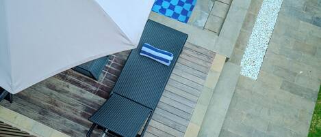 A rooftop terrace with a checkered blue and white floor, a covered seating area, and a pool with a white pebble border.