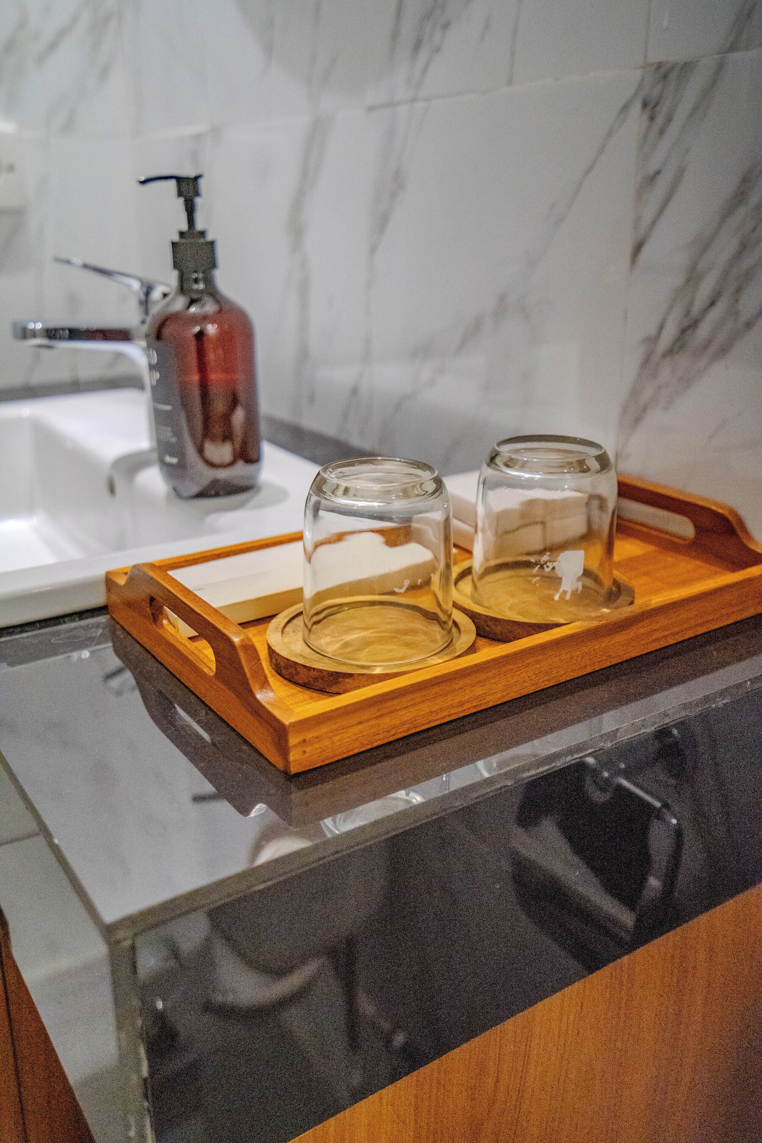 A wooden tray with two glass containers on a kitchen counter.