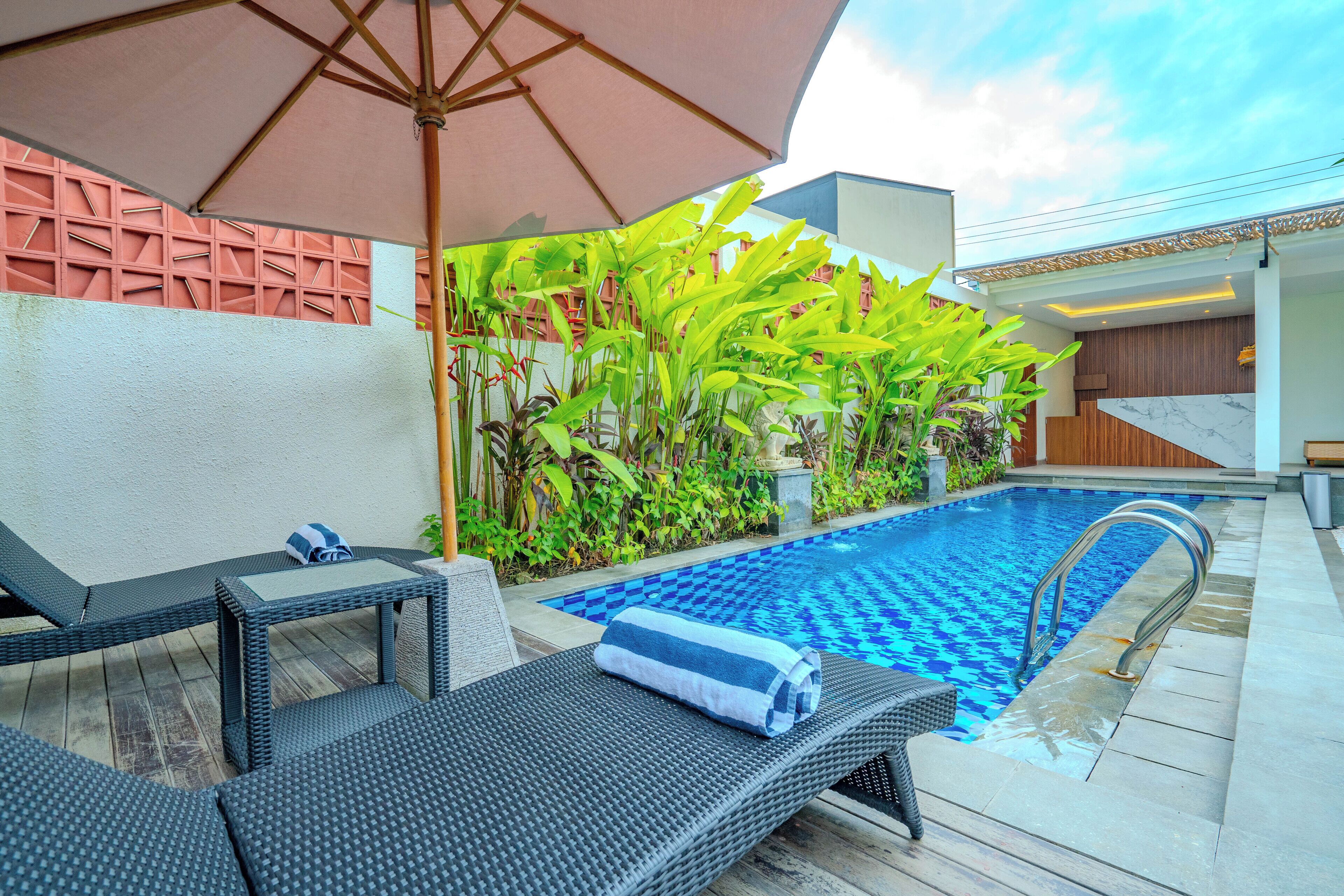 A poolside area with lounge chairs, a pool, and a covered seating area.