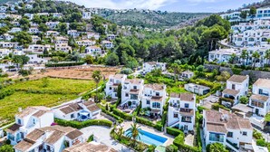 A coastal residential area with white buildings, a swimming pool, and lush greenery.