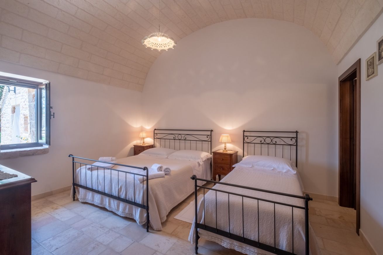 A bedroom with two beds, a window, and a chandelier.