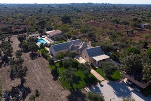Vue aérienne d’une propriété comprenant une piscine, plusieurs bâtiments et une végétation luxuriante.