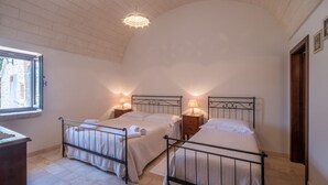 A bedroom with two beds, a window, and a chandelier. - Authentic Apulian Reatreat inside Trulli with private pool (Castellana Grotte)