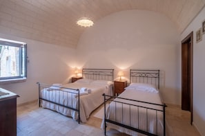 A bedroom with two beds, a window, and a chandelier.