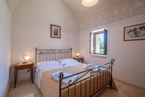 Une chambre à coucher avec un lit, deux tables de chevet avec des lampes, une fenêtre et un tableau au mur.