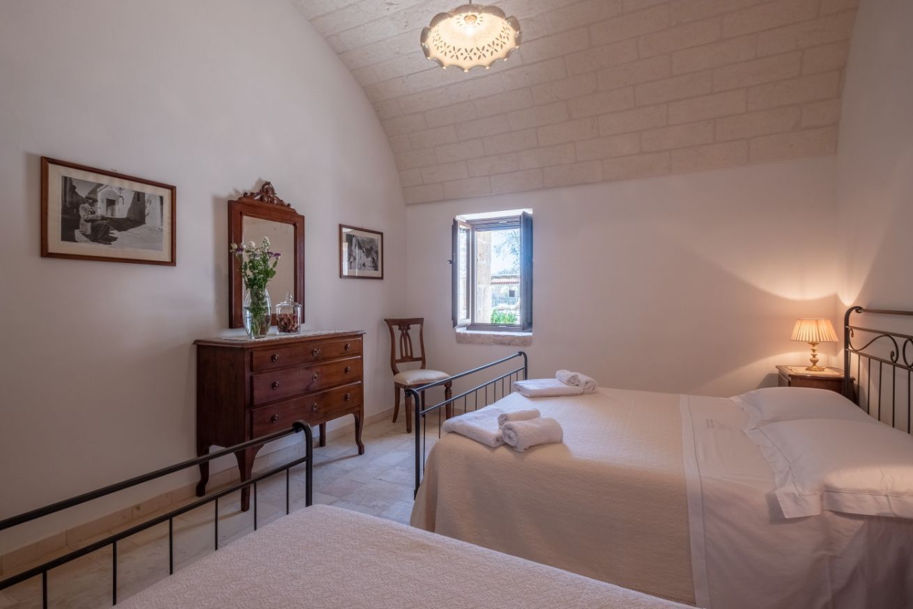 Une chambre avec deux lits, une commode, un miroir et des tableaux encadrés accrochés au mur.