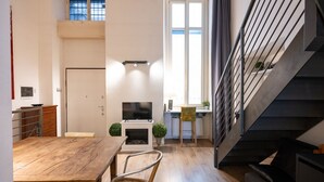 A modern interior with a dining area, a fireplace, a television, and a staircase. - Atriums Apartment Casa di Giulio (Torino)