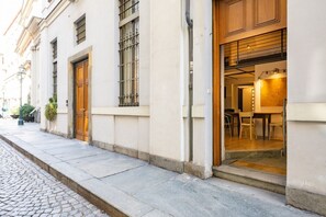 Un edificio con calle adoquinada, grandes puertas de madera y un interior visible que incluye un comedor.