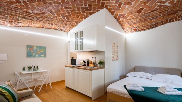 A compact room with a kitchenette, a bed, and a small seating area.