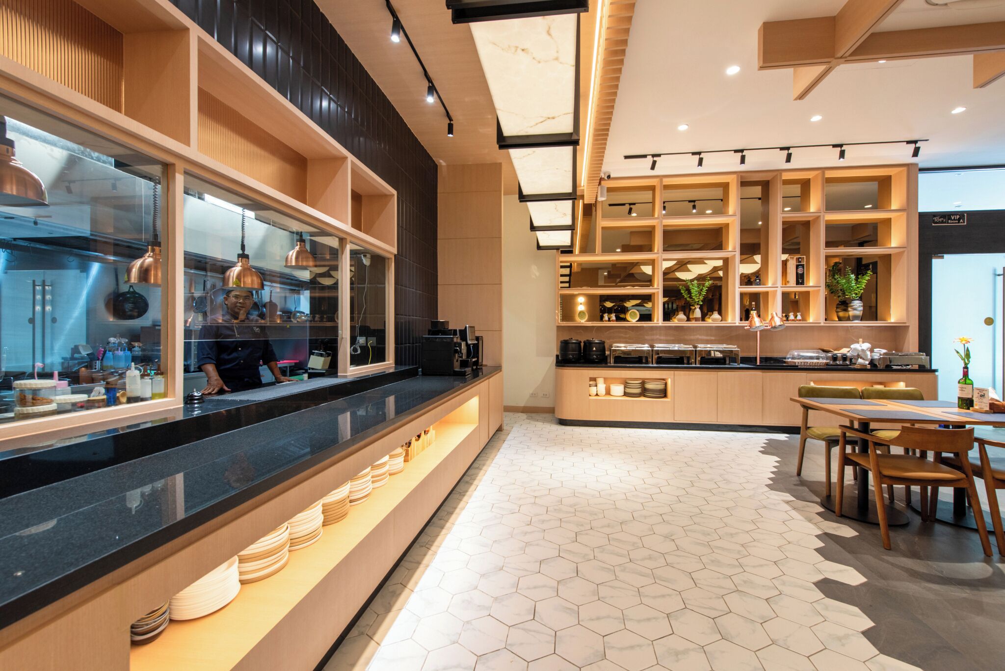 A modern kitchen with a long counter, wooden cabinets, and a hexagonal tile floor.