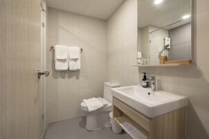 Un baño moderno con inodoro, lavabo y zona de ducha.
