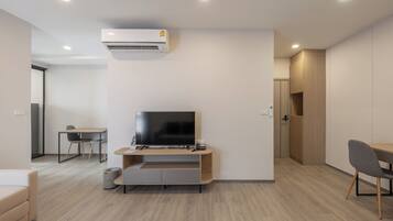 A modern living room with a flat-screen TV, wooden furniture, and built-in cabinets.