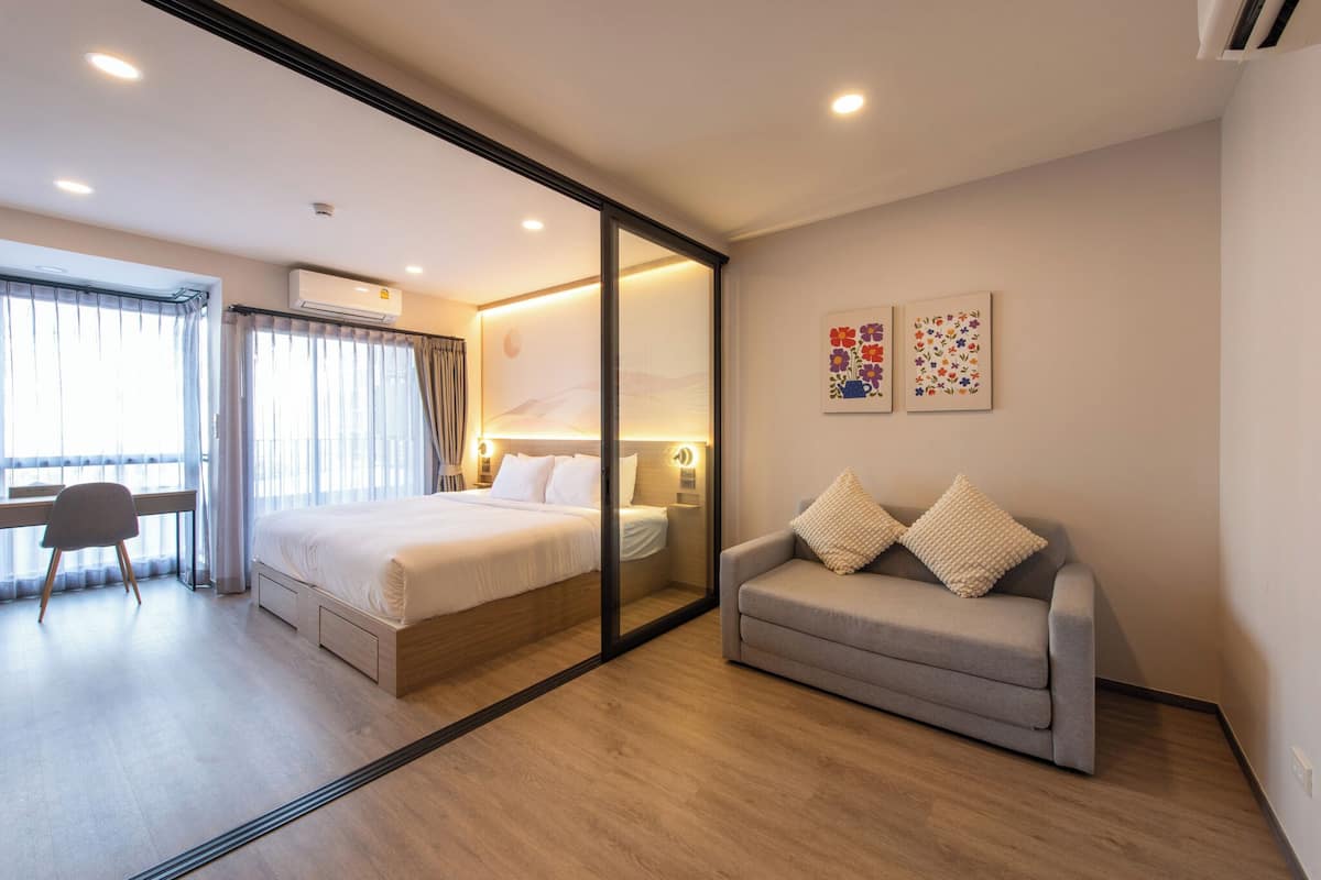 Ein modernes Hotelzimmer mit Bett, einer Couch, einem Schreibtisch und einem großen Fenster.