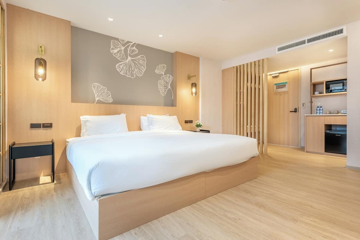 Ein modernes Hotelzimmer mit einem großen Bett, Holzvertäfelung, einer Wandleuchte und einem kleinen Nachttisch.