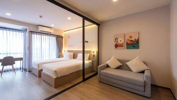 A hotel room with a bed, a sofa, a desk, and a chair.