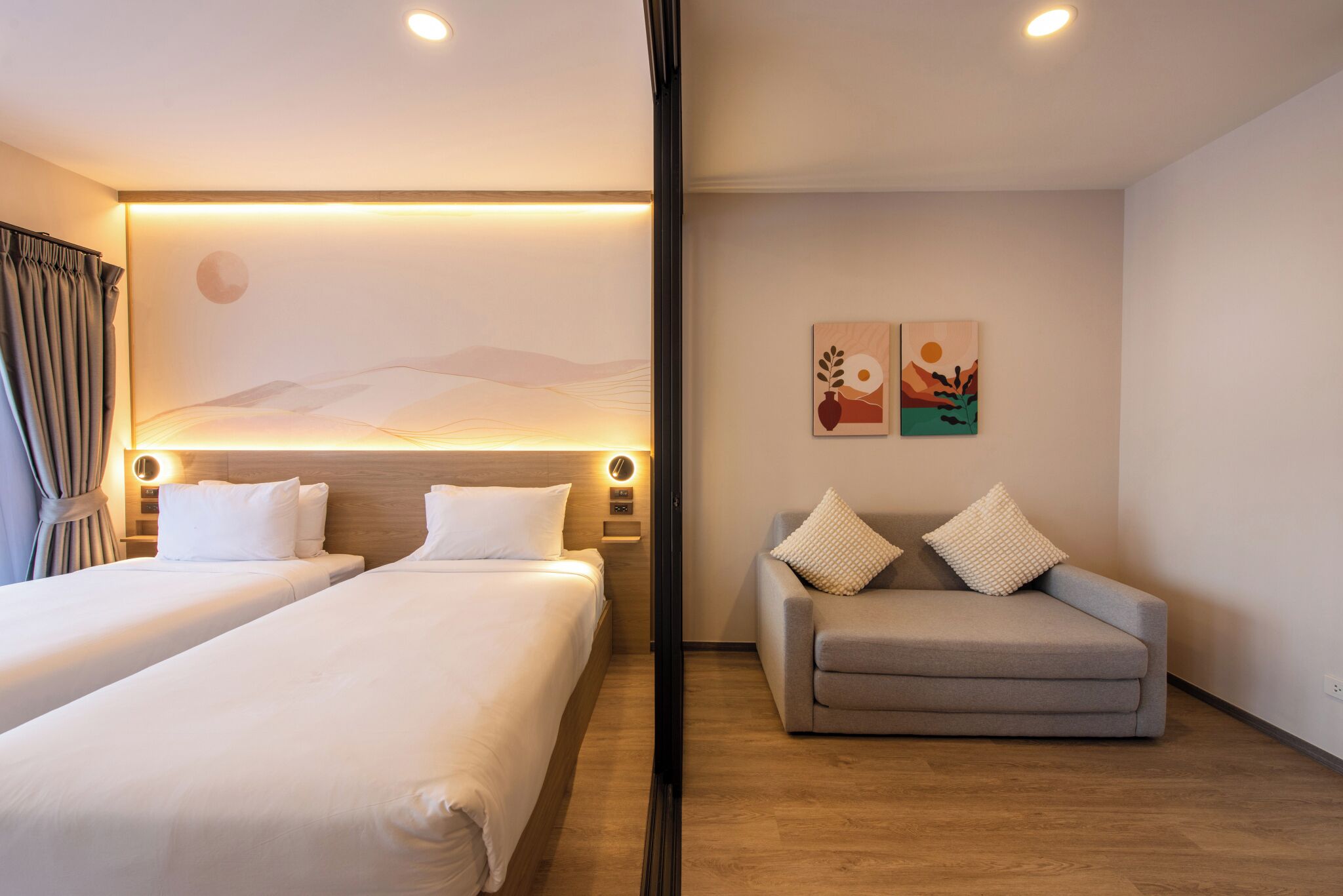 A hotel room with two beds, a sofa, and a wall with artwork.
