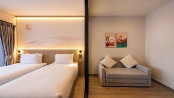 A hotel room with two beds, a sofa, and a wall with artwork.