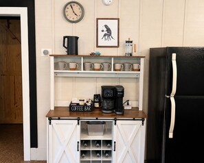 A kitchen with a coffee station, a clock, and a framed picture.