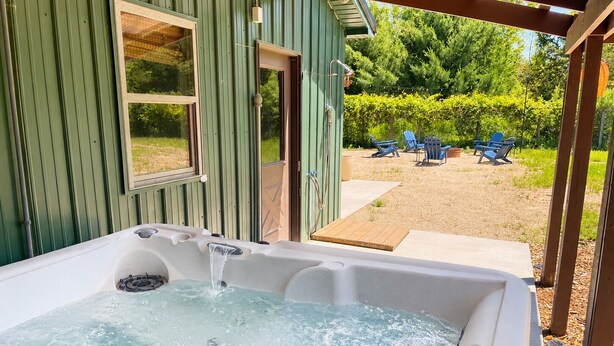 Ein Whirlpool mit einer Holterrasse und Blick auf einen Garten mit Stühlen.