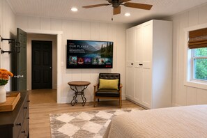 A bedroom with a bed, a chair, a table, a TV, and a wardrobe.