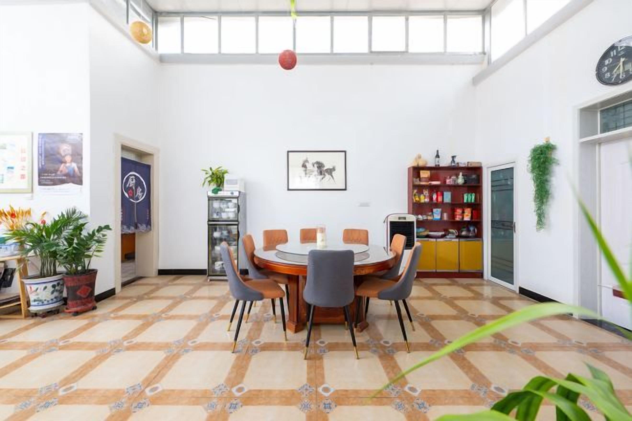 A dining area with a round table and chairs, a bookshelf, and a potted plant.