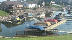 Een jachthaven met aangemeerde boten, een gazon op de voorgrond en huizen achterin.