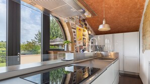 Ett modernt kök med en stor köksö, rostfria vitvaror och utsikt över grönområden utanför.