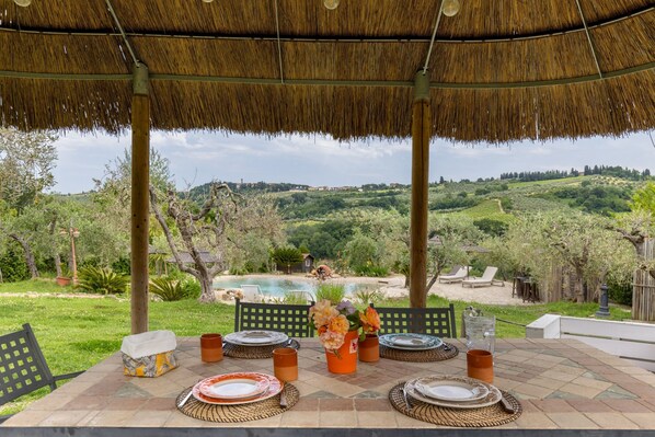 Une table dressée à l’extérieur, avec vue sur une piscine et un espace verdoyant.