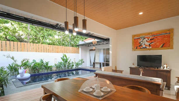 A modern dining area with a wooden table, chairs, and a glass-top table with a decorative cover.