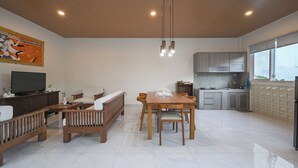 A modern living room with a wooden dining table, sofas, and a TV.