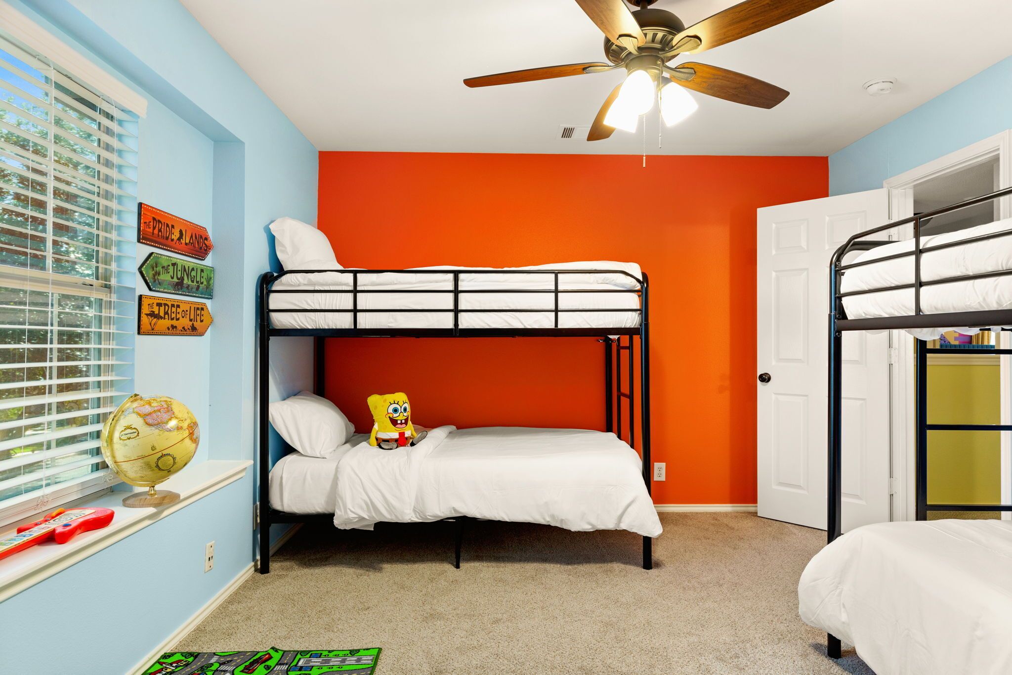 Ein Schlafraum mit Etagenbetten, Deckenventilator, Globus und Leerschildern an der Wand.