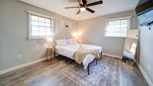 Une chambre à coucher avec un lit, un ventilateur de plafond, deux lampes de chevet, un tapis et un miroir.