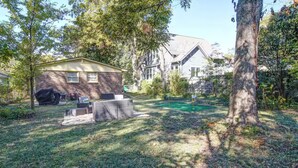 Un jardin avec un espace barbecue, un coin salon abrité et un petit espace de jeux.