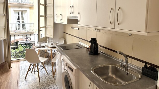 A modern kitchen with a washing machine, a sink, and a dining area with a balcony view. - EL BALCÓN MÁLAGA MALAGA (MALAGA)