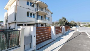 A multi-story residential building with balconies, a gated entrance, and a paved driveway.