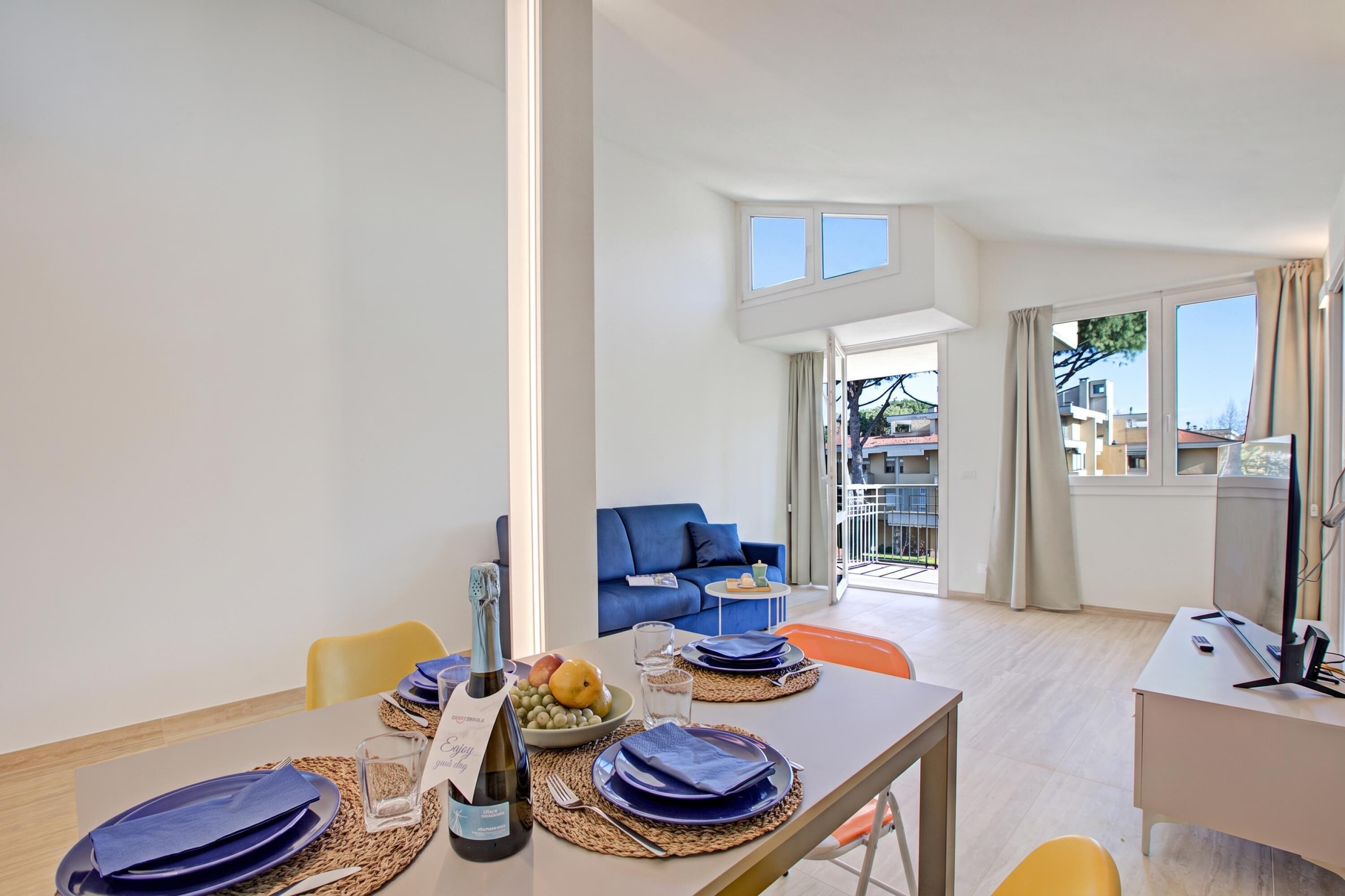 A modern living room with a dining area, a sofa, and a balcony with a view.